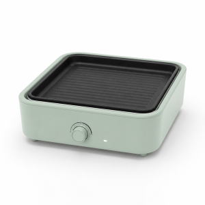 multi cooker with mint green housing, black interchangeable plates, and front temperature dial